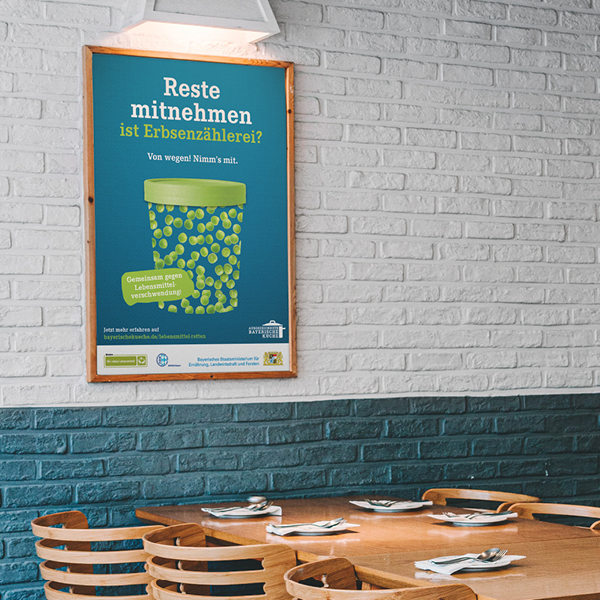 EIn Bild mit dem Motiv "Wir retten Lebensmittel" hängt an der Wand eines Cafes.